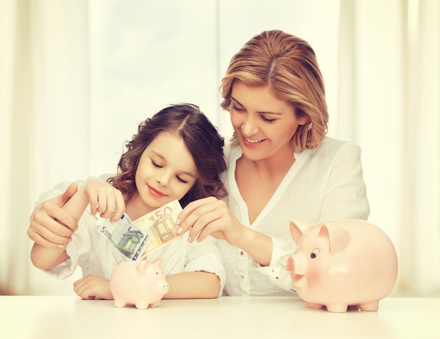 mãe e filha com cofrinhos e dinheiro de papel