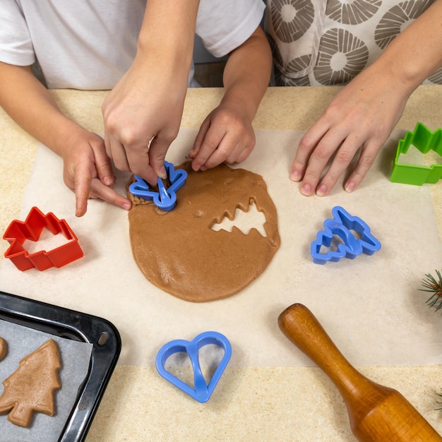 Foto mãe e filha com cortadores de biscoitos fazem biscoitos de massa na cozinha da casa
