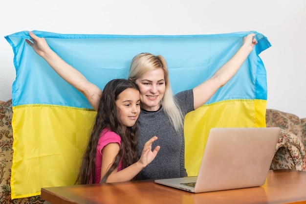 Mãe e filha com laptop e bandeira da Ucrânia