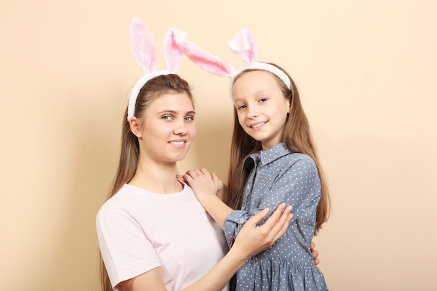 Mãe e filha com orelhas de coelho em um fundo colorido