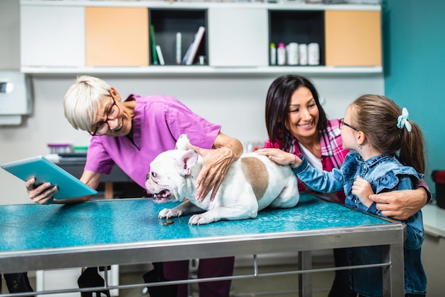 Mãe e filha com seu buldogue francês no veterinário.