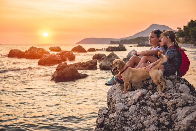 Mãe e filha com um cachorro, caminhadas à beira-mar