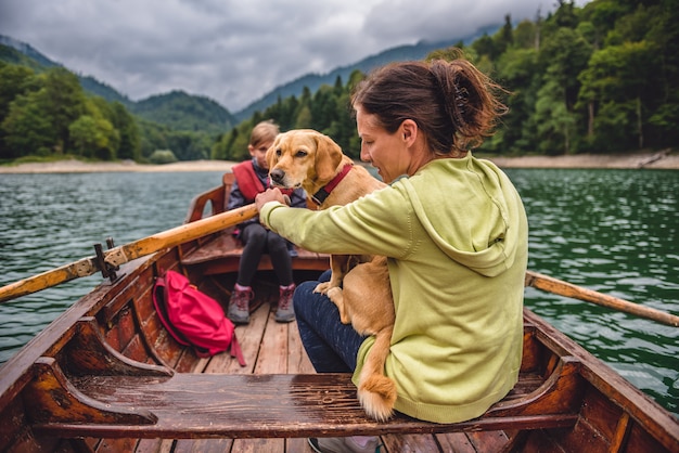 Mãe e filha com um cachorro remando um barco