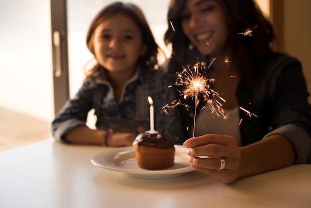 Mãe e filha comemorando aniversário com cupcake e estrelinhas