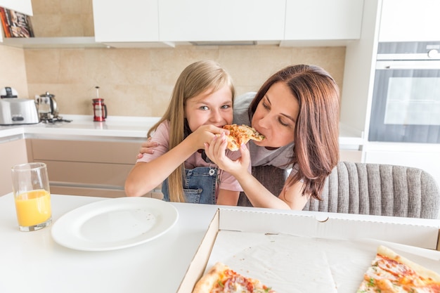 Mãe e filha comendo uma pizza saborosa