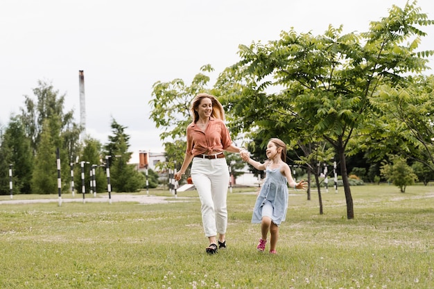 Mãe e filha correm no parque e se divertem Valores e tradições familiares Feliz infância de uma criança Mãe brinca com sua filha