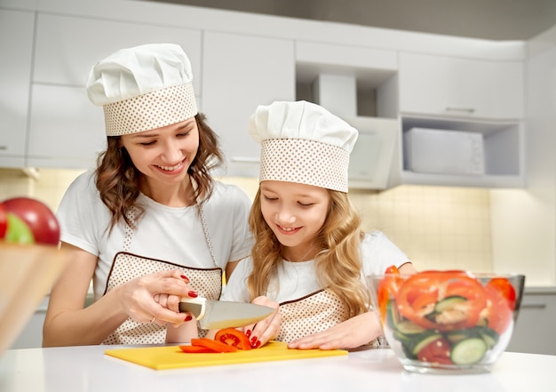 Mãe e filha cortar legumes para salada fresca.