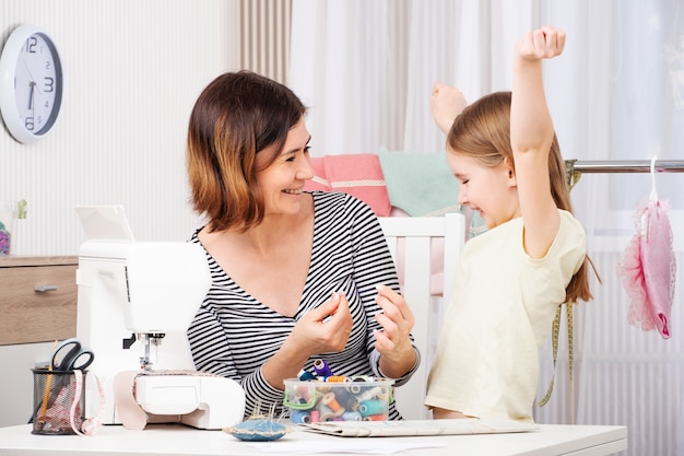 Mãe e filha costuram roupas