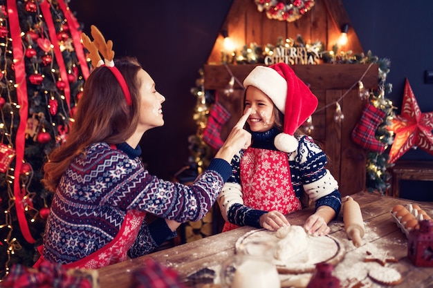 Mãe e filha cozinhando biscoitos de Natal.