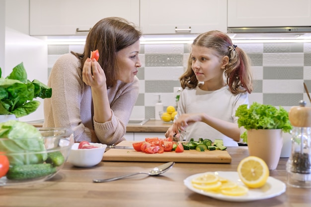 Mãe e filha cozinhando na salada de legumes de cozinha