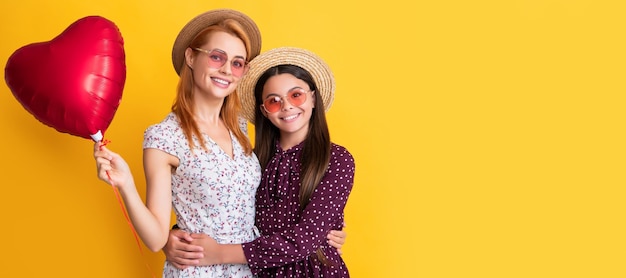 Mãe e filha criança banner cópia espaço isolado fundo mãe e filha felizes seguram balão de coração de amor em fundo amarelo