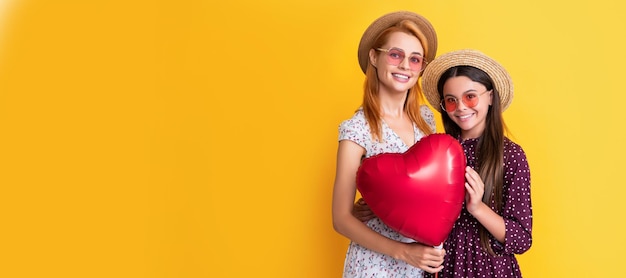 Mãe e filha criança banner espaço de cópia isolado fundo positivo mãe e filha segurando balão de coração de amor em fundo amarelo