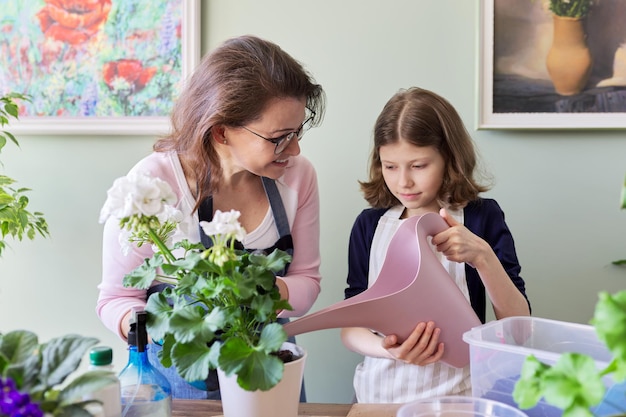 Mãe e filha criança juntos cuidam de plantas de interior em vasos, flor regadora de menina de regador. Hobbies e lazer, cuidados, família, planta de casa, conceito de amigos em vasos domésticos