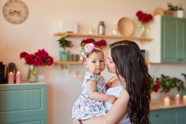 Mãe e filha da família com flores de peônias na cozinha em casa. Feliz mãe e filha. Família feliz.