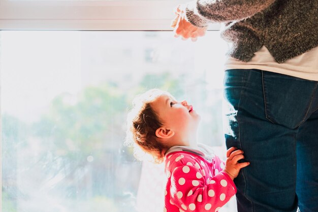 Foto mãe e filha de pé na janela