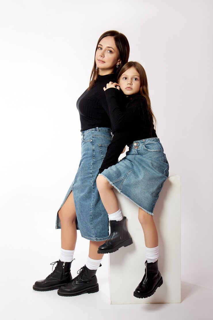 Mãe e filha de retrato de moda beleza em uma blusa preta de gola alta e saia jeans azul. Mulher e menina, família