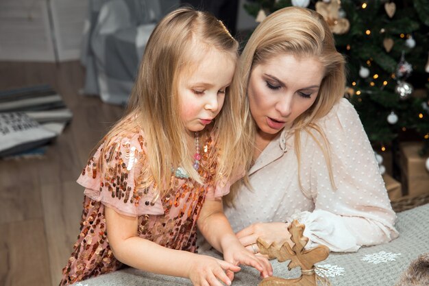 Mãe e filha decoram a árvore na sala. amando família dentro de casa, feriados, celebração, conceito de família e pessoas