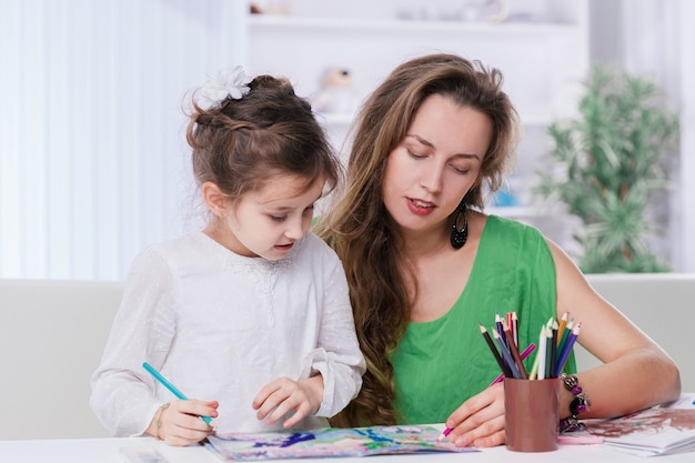 Mãe e filha desenhando à mesa. o conceito de criatividade infantil