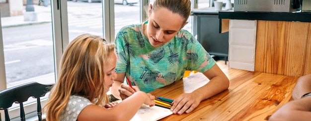 Mãe e filha desenhando juntas com lápis de cor e caderno