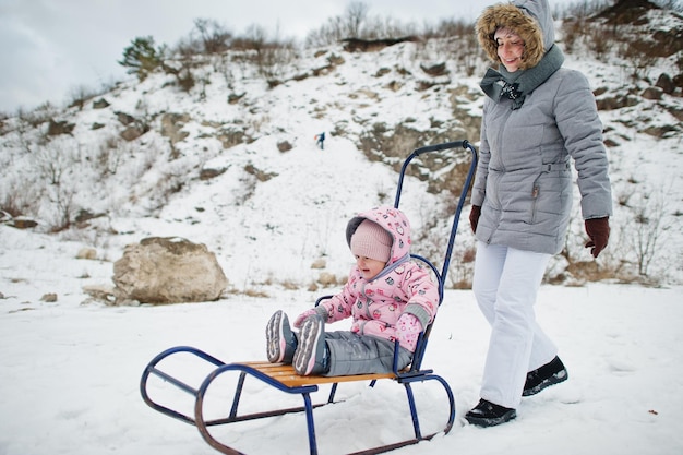 Mãe e filha desfrutam de um passeio de trenó. Trenó infantil. Garoto andando de trenó no inverno.