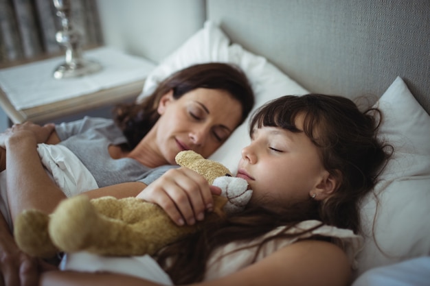 Mãe e filha dormindo na cama