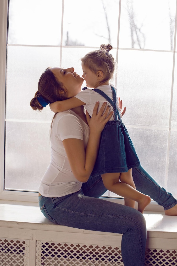 Foto mãe e filha em camisetas brancas sentadas na janela do quarto