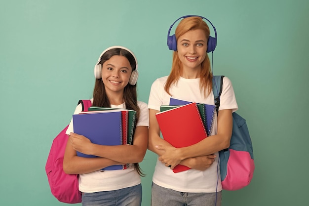 Mãe e filha em fones de ouvido seguram notebook e mochila prontos para estudar ebook