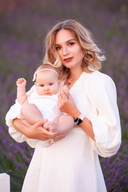 Mãe e filha em lindos vestidos brancos em um campo de lavanda no verão ao pôr do sol.