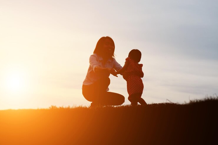 Foto mãe e filha em terra contra o céu durante o pôr-do-sol