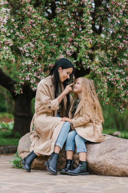 Mãe e filha em um jardim florescente de primavera mãe ama seu bebê família feliz em um lindo dia de primavera dia das mães