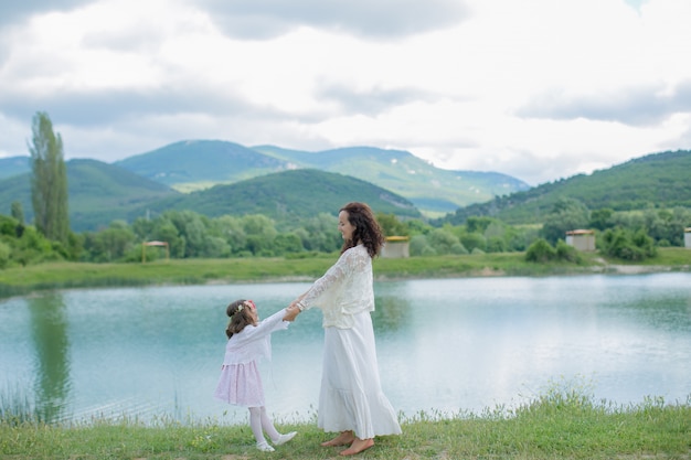 Mãe e filha em um pasto perto de um lago de montanha