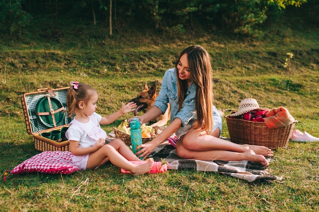 Mãe e filha em um piquenique com um cachorro