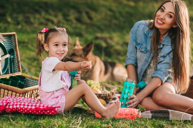 Mãe e filha em um piquenique com um cachorro