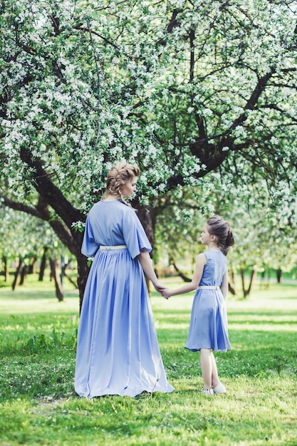 Mãe e filha em vestidos na natureza