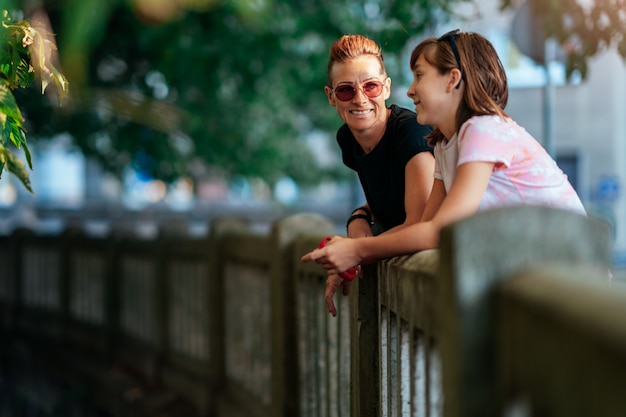 Mãe e filha encostam-se a cerca tendo conversa