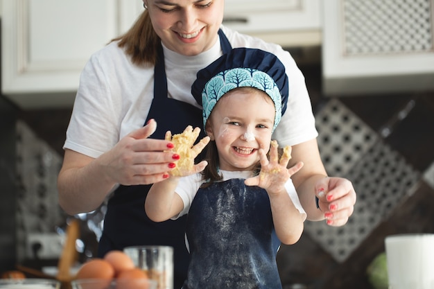 Mãe e filha engraçada mostrando as mãos na massa na cozinha