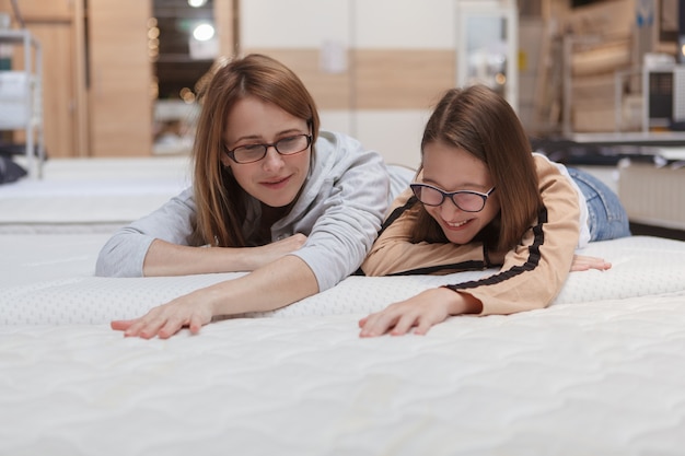 Mãe e filha escolhendo uma nova cama ortopédica para comprar na loja de móveis