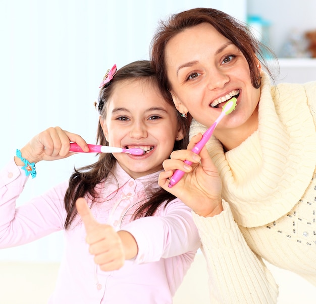 Mãe e filha escovam os dentes.