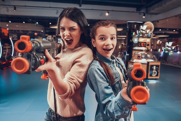 Mãe e filha estão atirando armas no arcade.