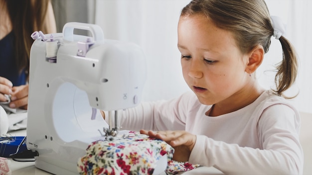 Mãe e filha estão costurando juntos uma máquina.