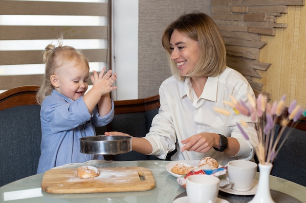 Mãe e filha estão cozinhando biscoitos e se divertindo na cozinha.