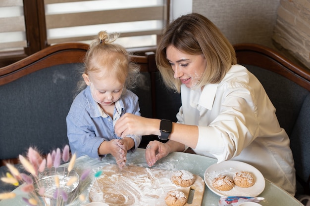 Mãe e filha estão cozinhando biscoitos e se divertindo na cozinha.