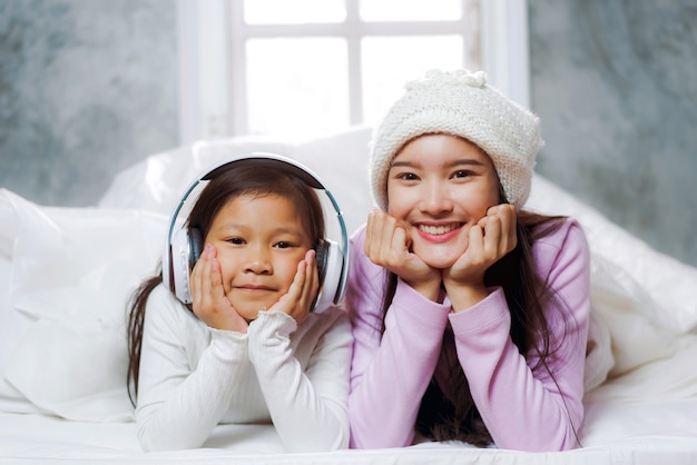 Mãe e filha estão deitados na cama e jogando