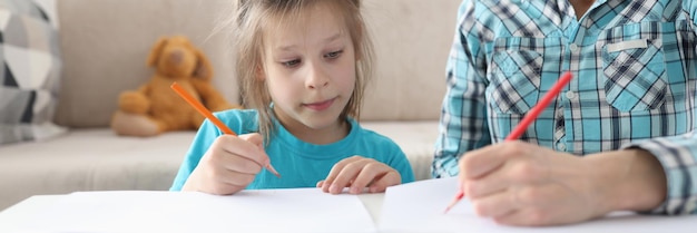 Mãe e filha estão desenhando na mesa em casa