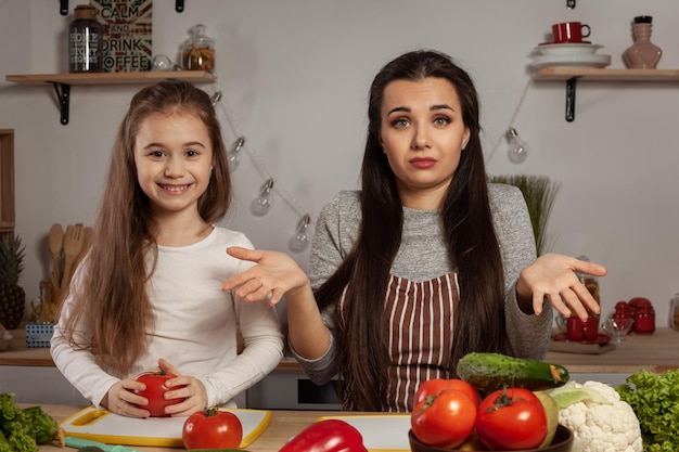 Mãe e filha estão fazendo salada de legumes e se divertindo na cozinha.