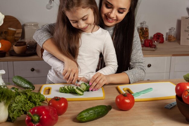 Mãe e filha estão fazendo salada de legumes e se divertindo na cozinha.