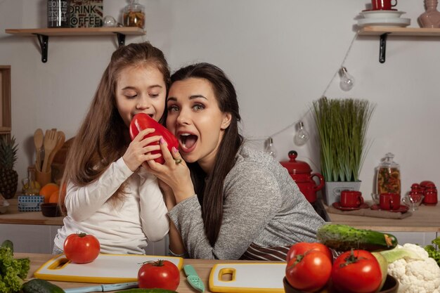 Mãe e filha estão fazendo salada de legumes e se divertindo na cozinha.