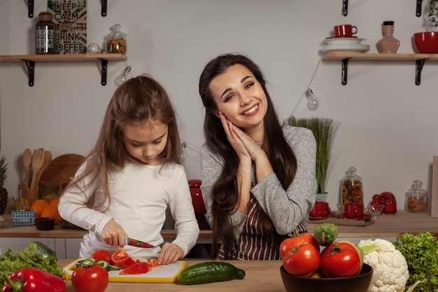 Mãe e filha estão fazendo salada de legumes e se divertindo na cozinha.