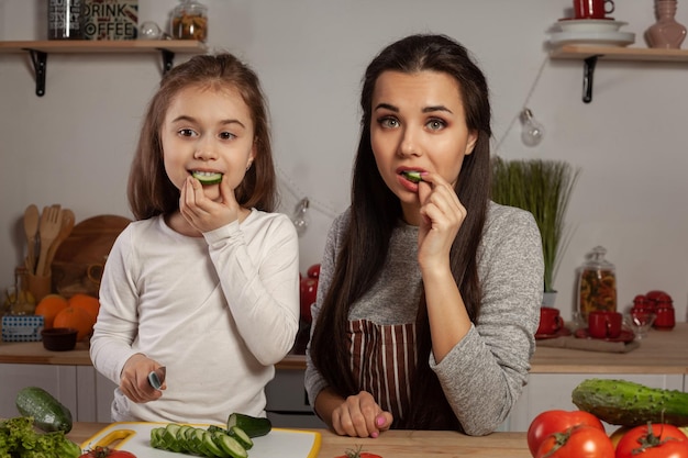 Mãe e filha estão fazendo salada de legumes e se divertindo na cozinha.