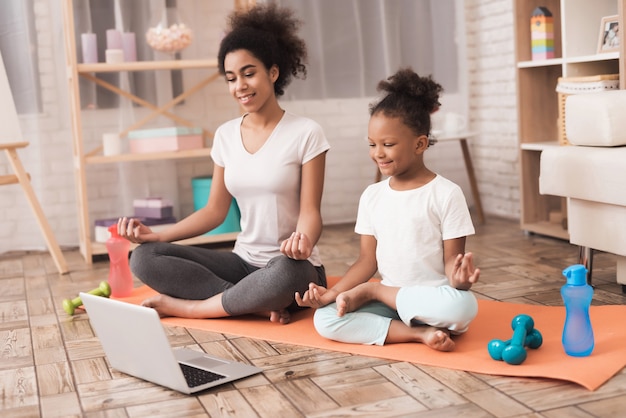 Mãe e filha estão fazendo yoga em casa.